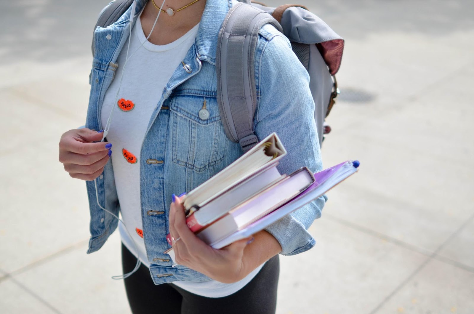 A picture of a medical student holding their books and walking to class with their backpack on